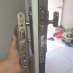 מנעולן ביבנה מאייל מחליף מנגנון פלדלת מנעולן ביבנה עם אופנוע שירות על רקע מגדלי יבנה הירוקה